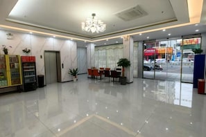 Un hall d’hôtel comprenant un comptoir d’accueil, un espace salon et un distributeur automatique.