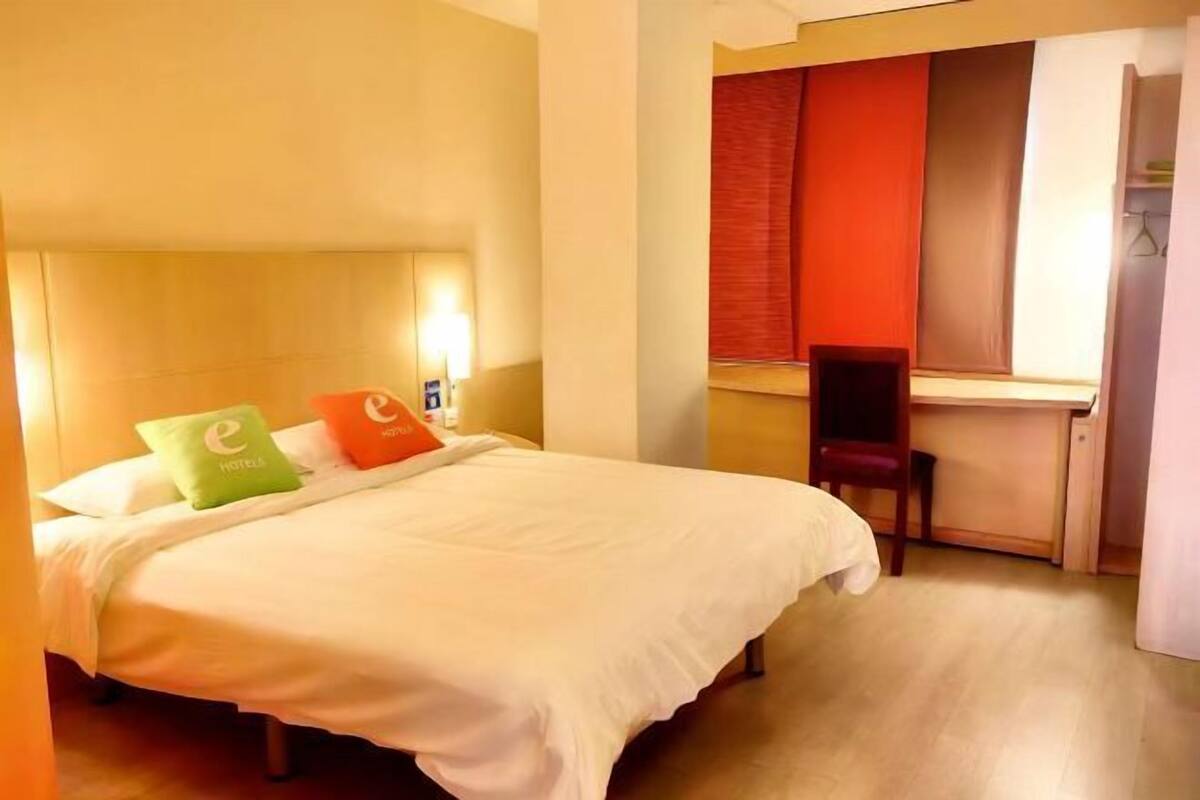 A hotel room with a bed, a desk, and a chair.