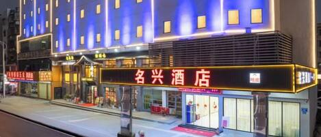 A hotel with a prominent sign, multiple floors, and a covered entrance area.