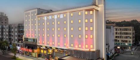 A multi-story hotel with a modern facade, multiple balconies, and a ground-level commercial area.