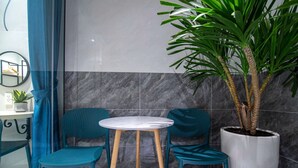A small, modern room with a marble wall, a round table, two teal chairs, a potted plant, and a mirror on the wall. - Bin Bin Hotel 14 - Near Vstar School D7 (Ho Chi Minh City)