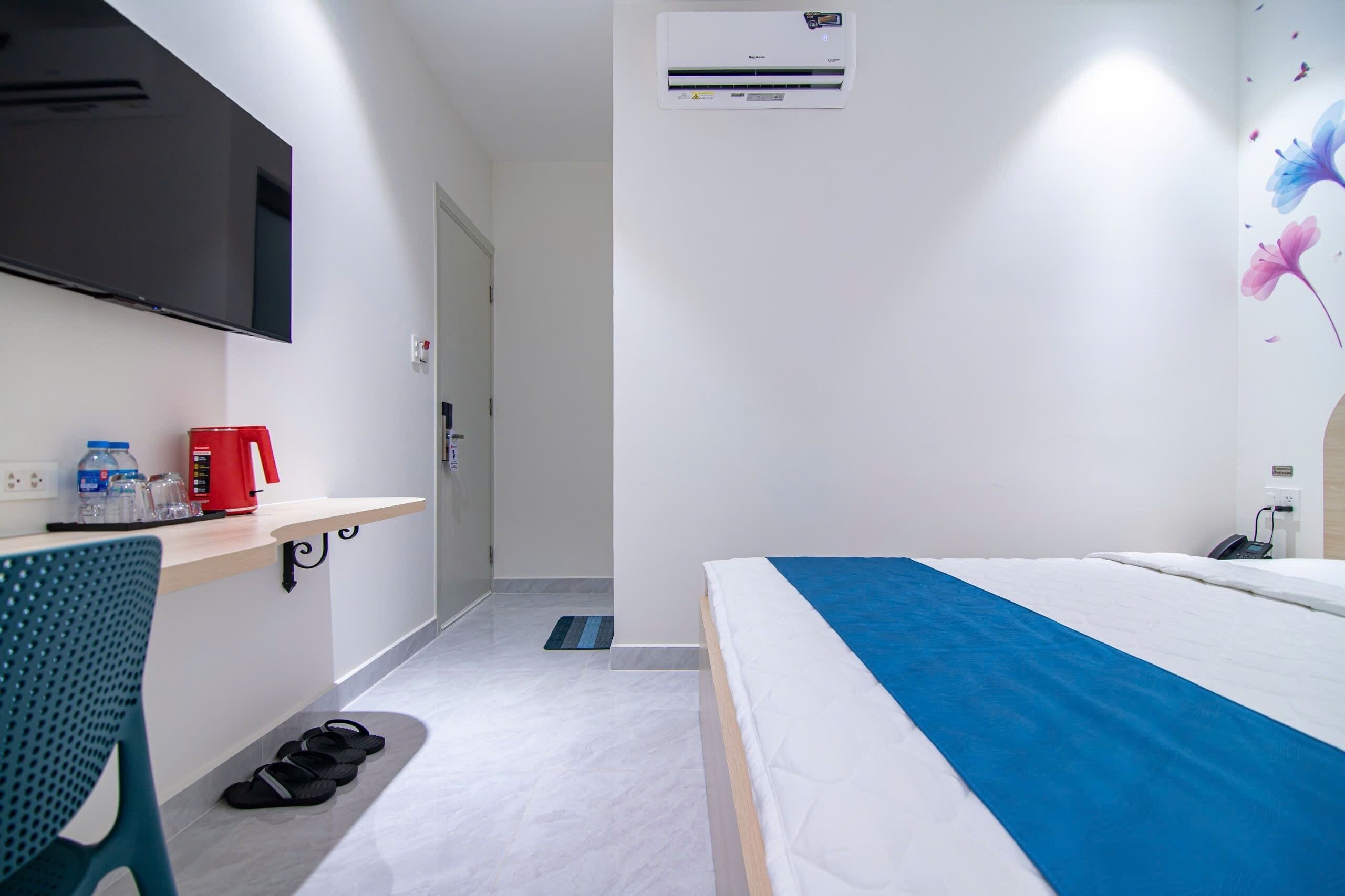 Ein Hotelzimmer mit einem Bett, einem Schreibtisch mit roter Kaffeemaschine, einem Flachbildfernseher und einer Klimaanlage.