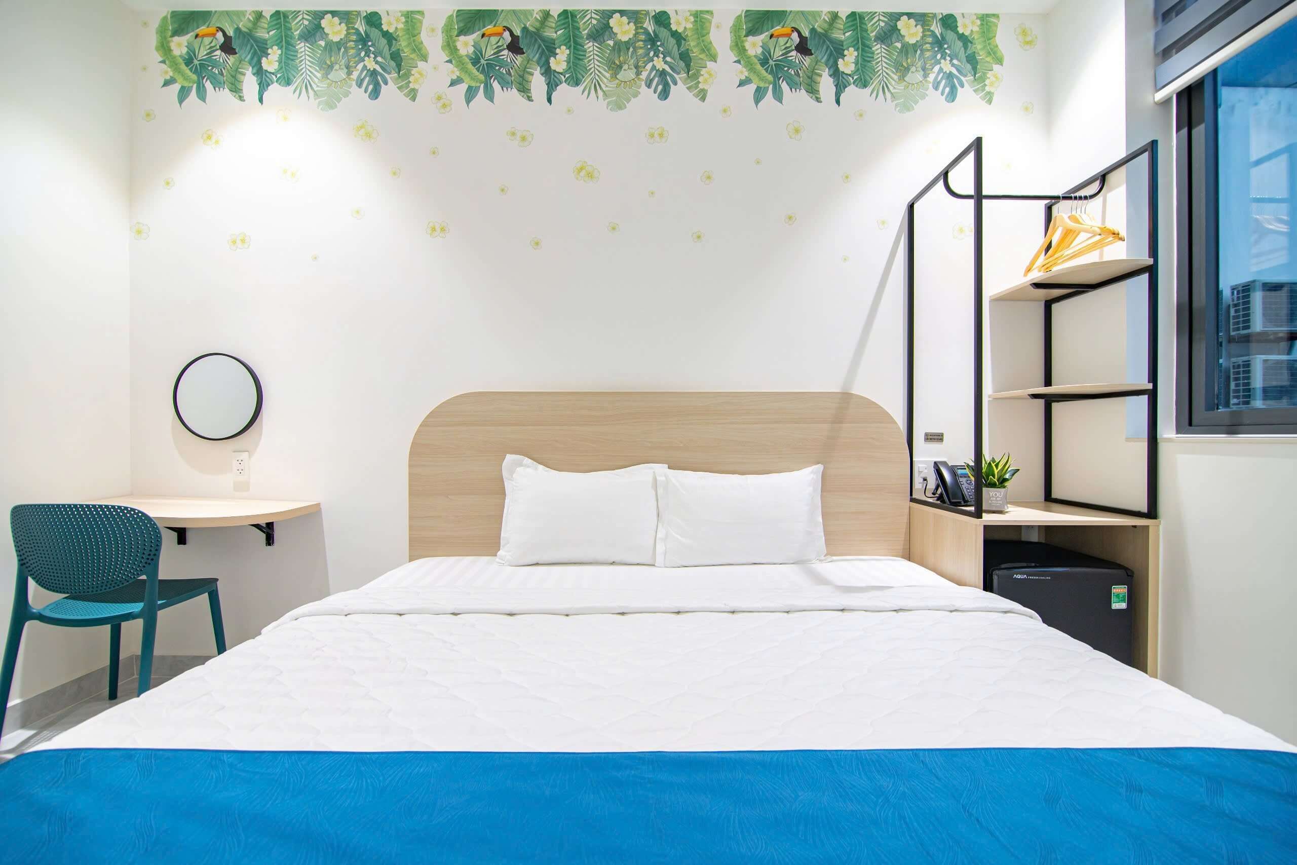 Ein Hotelzimmer mit Bett, Schreibtisch mit Stuhl, Ablagefläche mit Pflanze und Fenster.