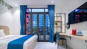 A hotel room with a bed, a desk, a chair, a TV, and a view of buildings through the window. - Bin Bin Hotel 14 - Near Vstar School D7 (Ho Chi Minh City)