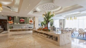 A modern hotel lobby with a marble reception desk, a dining area with chairs, and a large window providing natural light. - Fairyland International Hotel (Xiantao)