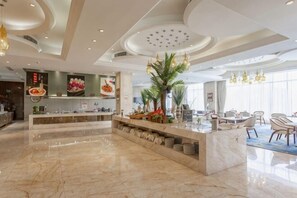Eine moderne Hotellobby mit einem Marmor-Empfangstresen, einem Essbereich mit Stühlen und einem großen Fenster, das natürliches Licht hereinlässt.