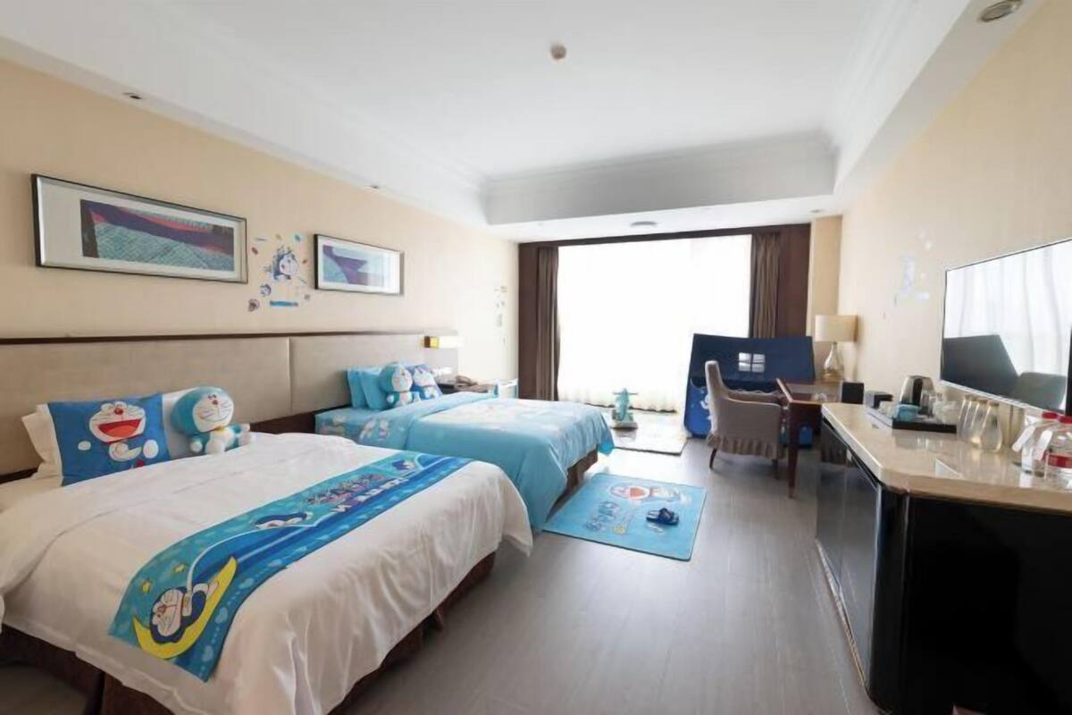 Hotelkamer met twee bedden, een bureau, een televisie en een balkon met uitzicht.