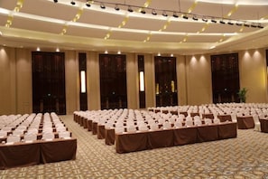 A large conference room with rows of tables and chairs, a patterned carpet, and a high ceiling with lighting fixtures. - Fairyland International Hotel (Xiantao)