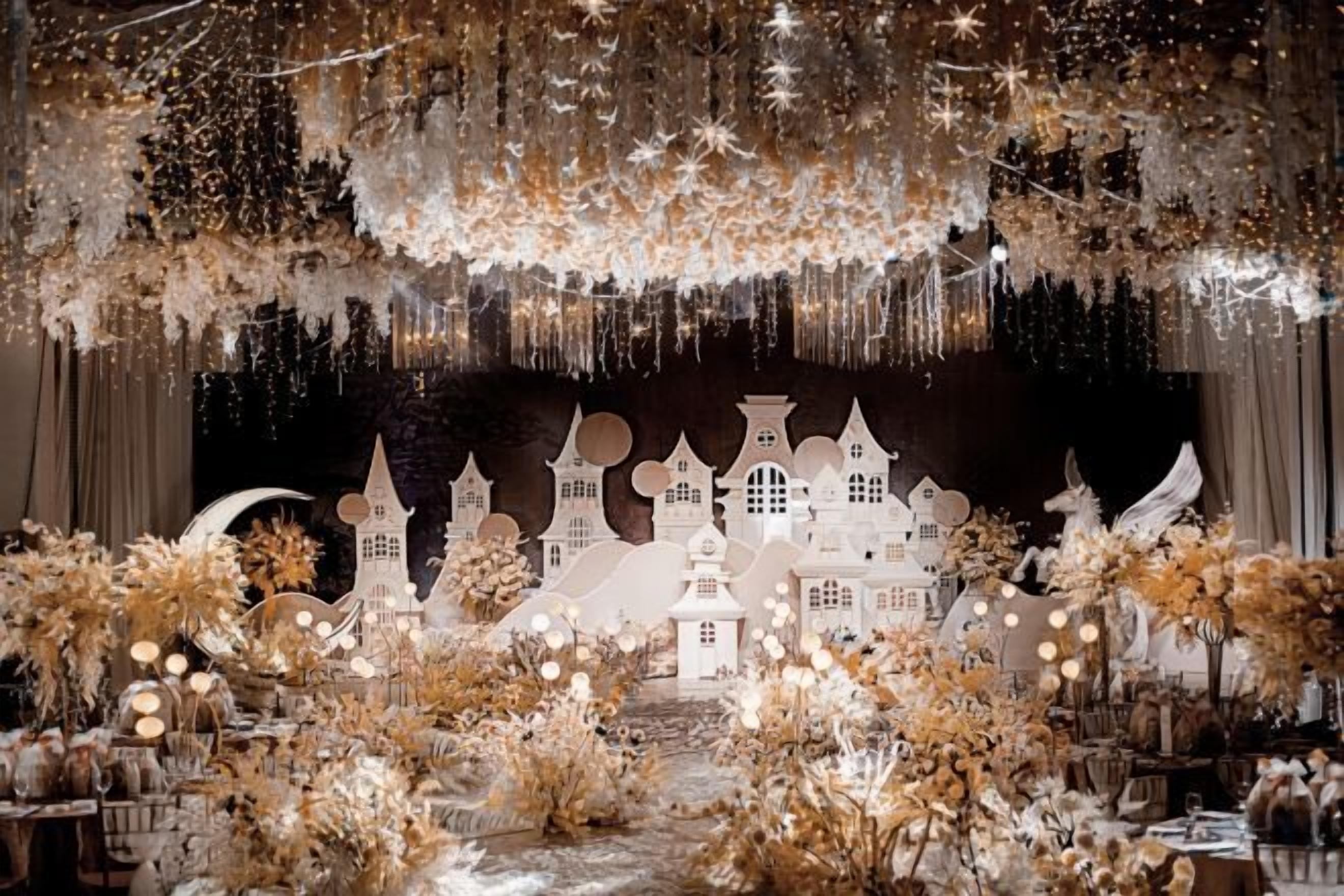A stage with a white backdrop, fairy lights, and a decorative village scene.