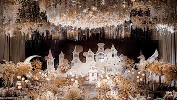 A stage with a white backdrop, fairy lights, and a decorative village scene.