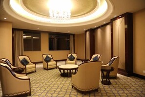 Une chambre d’hôtel dotée d’un espace salon circulaire, d’un lustre et d’une grande fenêtre.