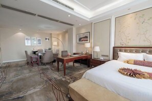 A hotel room with a large bed, a desk, a chair, and a small table.