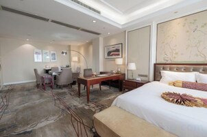 A hotel room with a large bed, a desk, a chair, and a small table.
