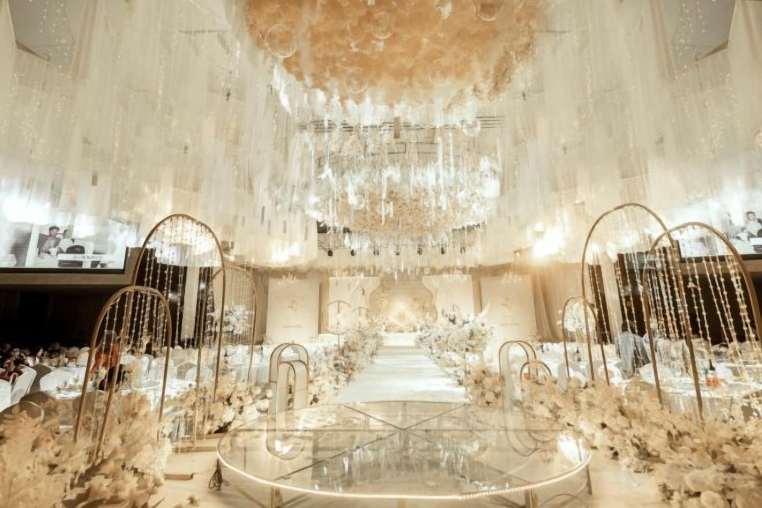 A grand hall with a central table, ornate chandeliers, and floral decorations.