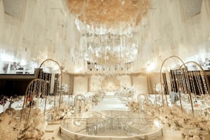 Un vaste hall doté d’une table centrale, de lustres somptueux et de décorations florales.