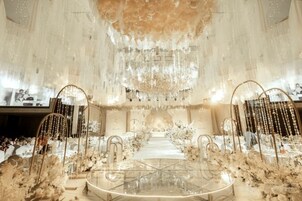 Un salón imponente con una mesa central, candelabros decorativos y adornos florales.