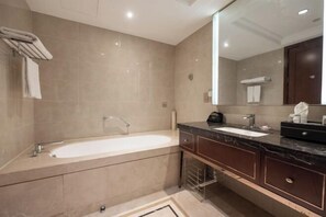 Bathroom features a bathtub, large mirror, and dark countertop.