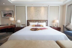 Une chambre d’hôtel avec un grand lit, deux tables de chevet, un bureau et une chaise.