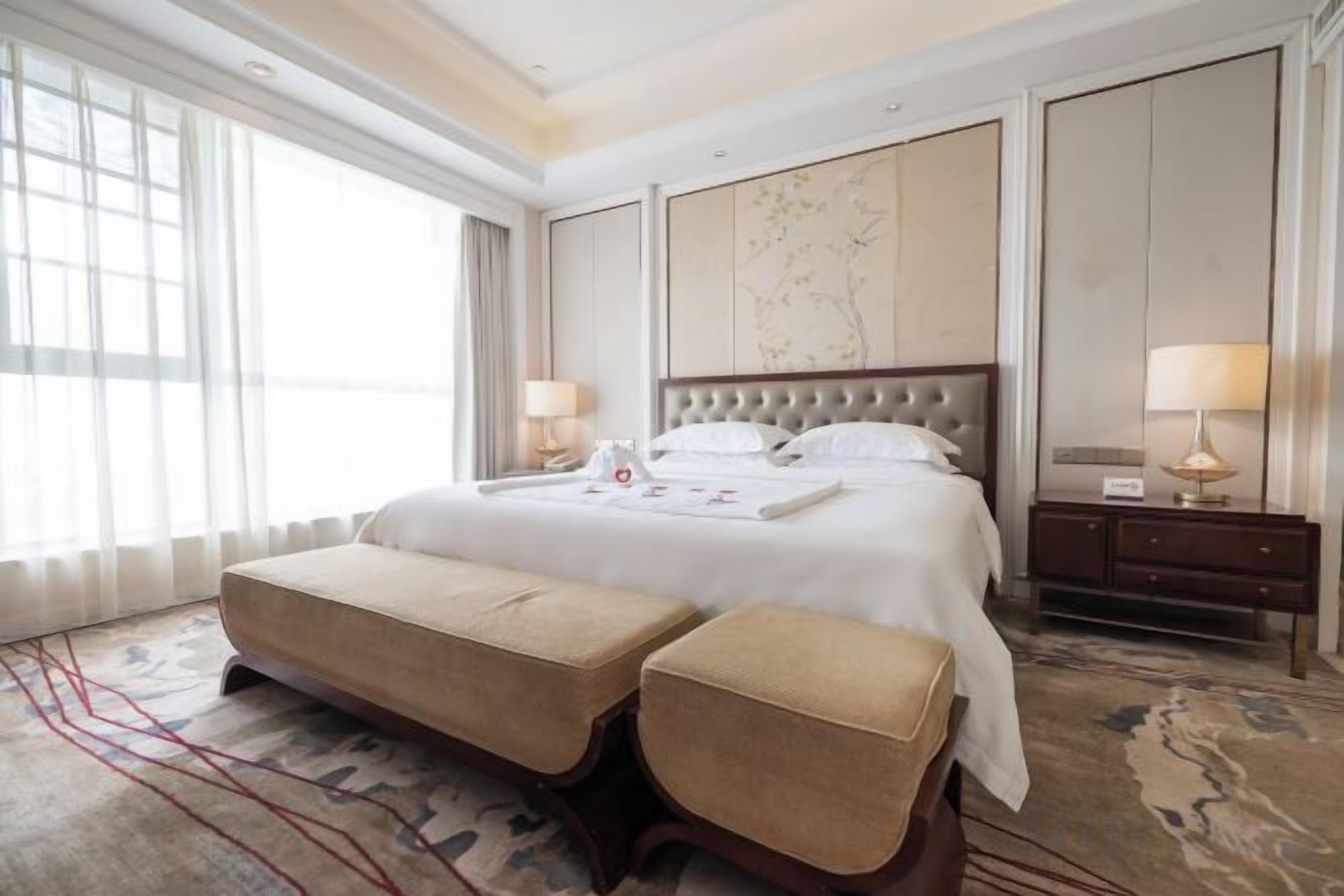 Habitación de hotel con una cama grande, una mesita de noche y un amplio ventanal.