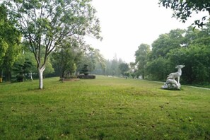 A park with a grassy area, a tree, and a sculpture.