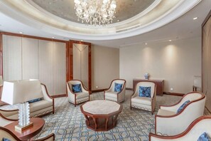 A hotel lobby with round tables, sofas, and a chandelier.