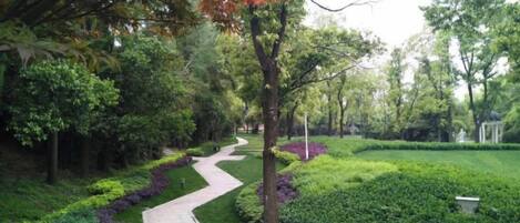 A pathway through a landscaped garden with trimmed hedges and trees.