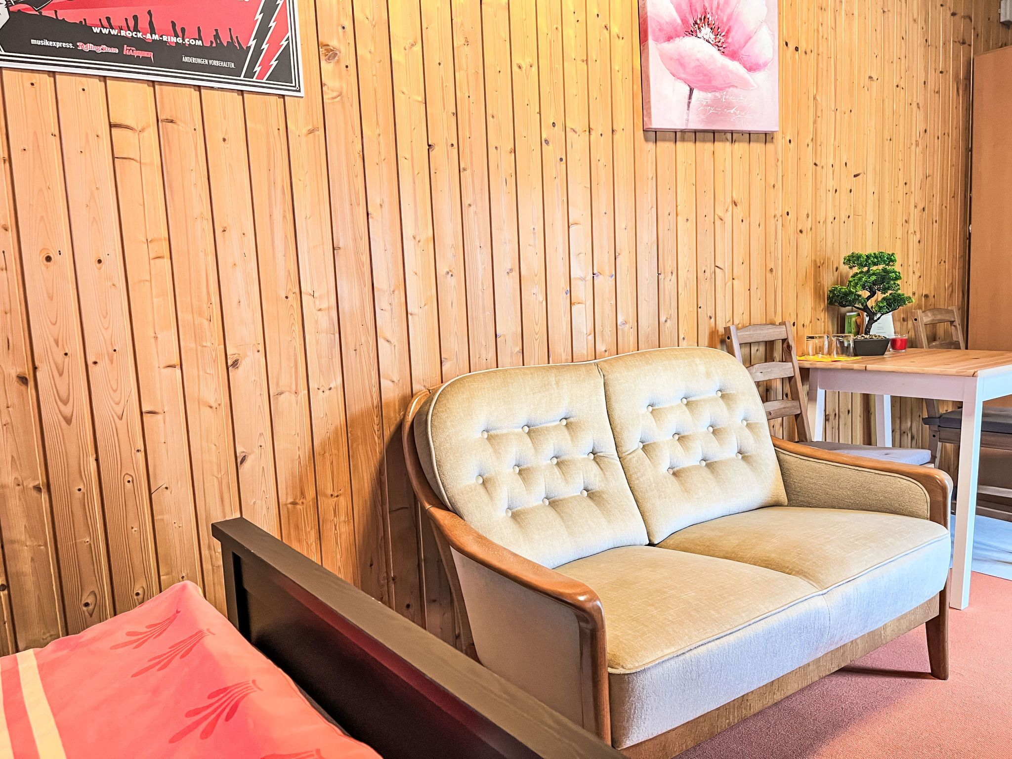 Une pièce aux murs lambrés, avec un canapé, une table à manger et une chaise.