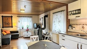 Una sala acogedora con sofá, mesa de comedor y zona de cocina con armarios y fregadero.