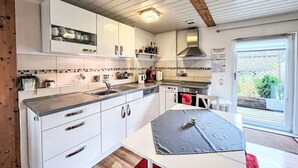 Una cocina moderna con armarios blancos, electrodomésticos de acero inoxidable y techo de madera.