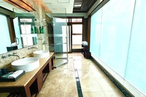 Ein modernes Badezimmer mit zwei Waschbecken, einer Glasdusche und einem großen Spiegel.