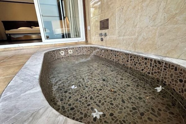Ein Whirlpool mit Steinplatten und einer Glastür zum Schlafzimmer.