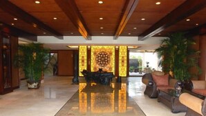 A lobby with a polished marble floor, a central decorative wall, and seating areas with wicker furniture. - Tianci Hot Spring Resort (Chongqing)