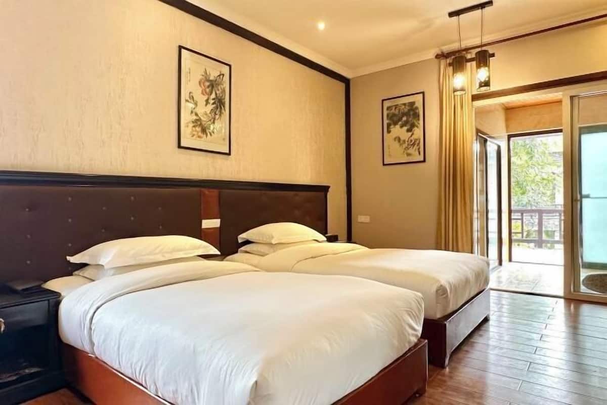A hotel room with a large bed, a nightstand, and a view of the outdoors.
