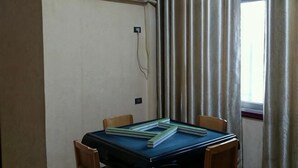 Ένα δωμάτιο με ένα τραπέζι, καρέκλες, μια μονάδα κλιματισμού, ένα παράθυρο με κουρτίνες κ αι μια πρίζα.