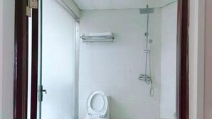 Ένα μικρό μπάνιο με τουαλέτα, ντους και μια κρεμάστρα για πετσέτες.