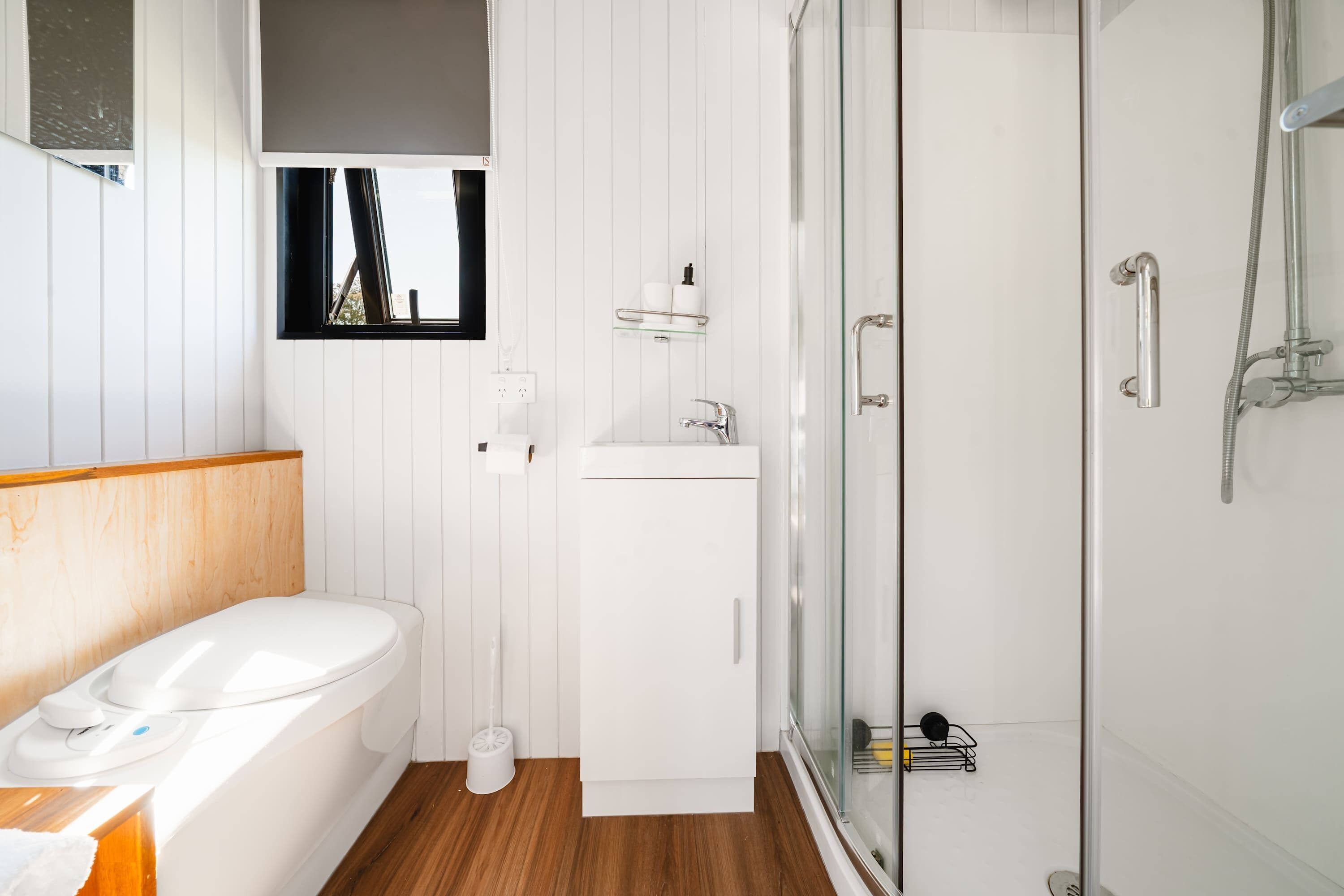 Ein modernes Badezimmer mit Toilette, Waschbecken und einer Duschkabine aus Glas.