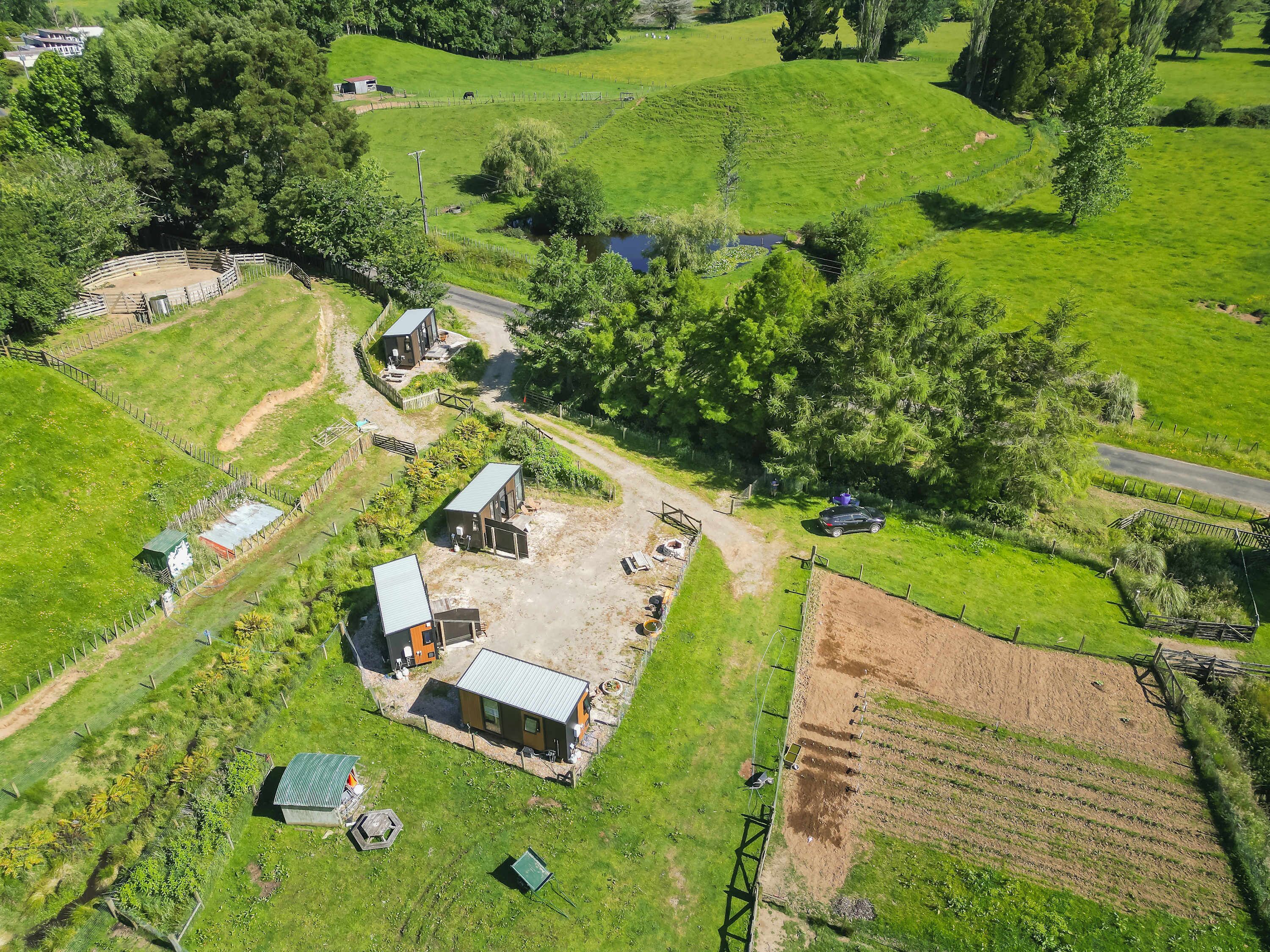 Vista aèria d'una finca rural amb diversos edificis, zones tancades i un camí de terra.