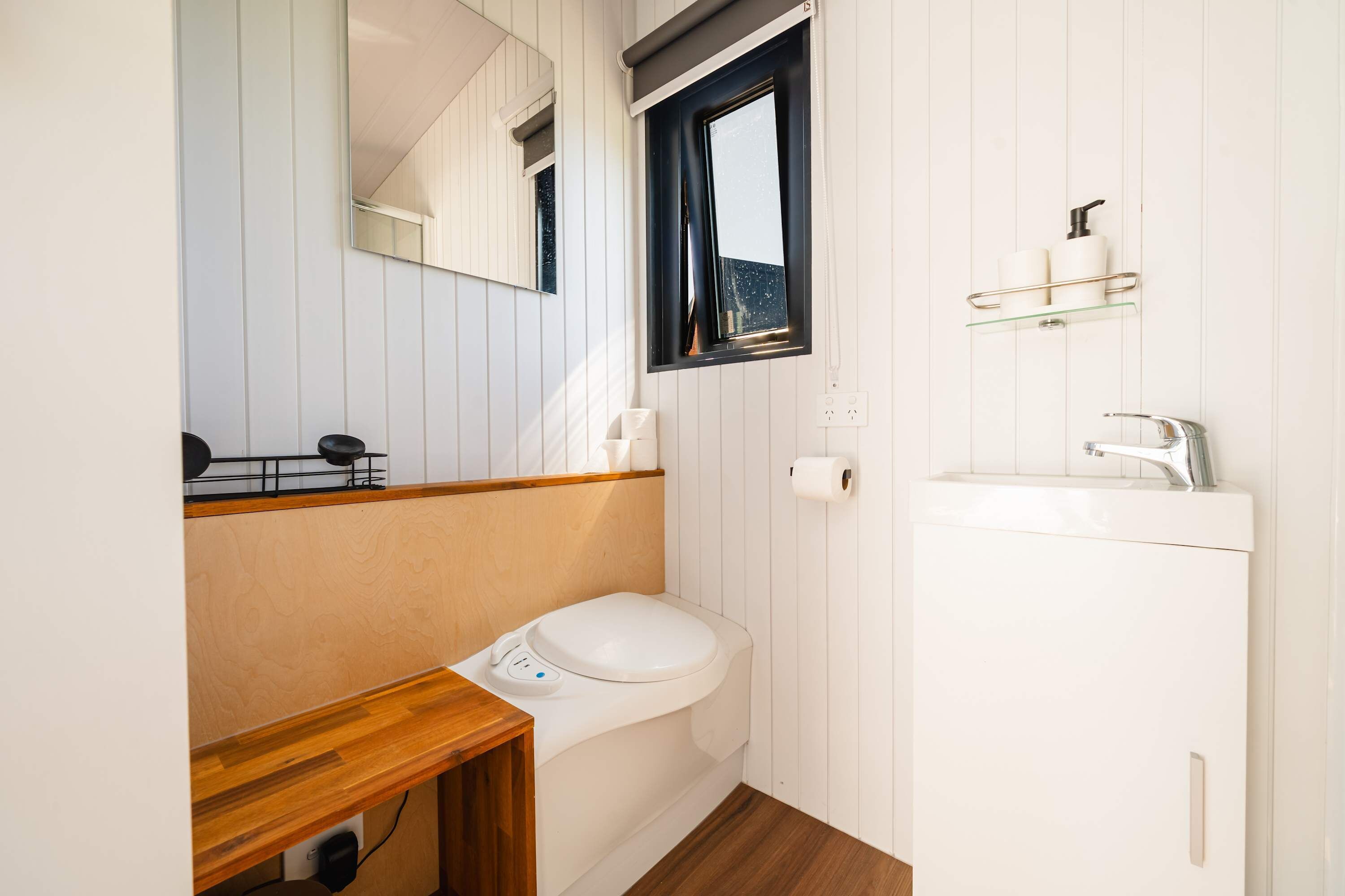Un baño pequeño con inodoro, lavamanos, espejo y ventana.