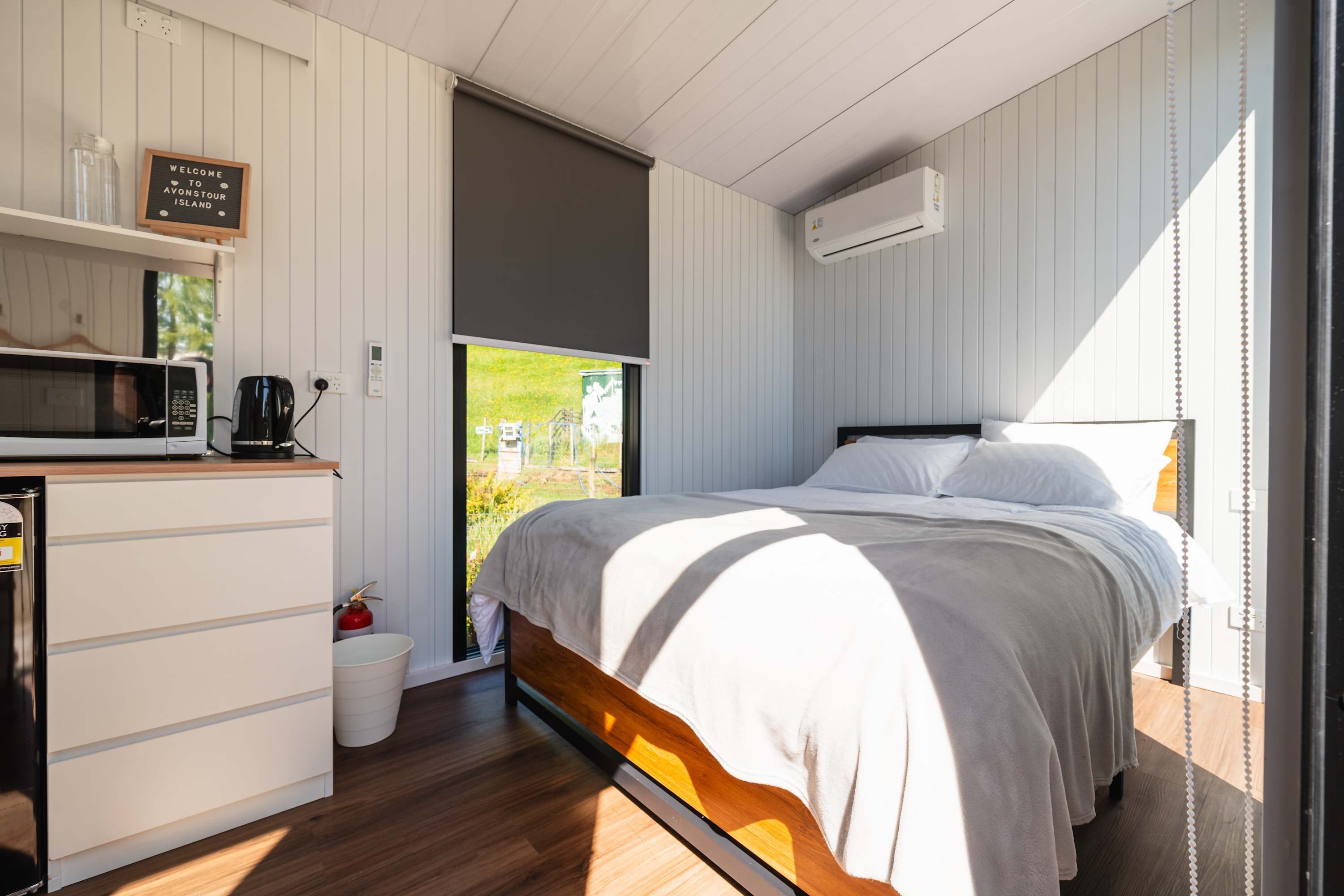 Un dormitorio con cama, una kitchenette pequeña con microondas y vistas a zonas verdes.