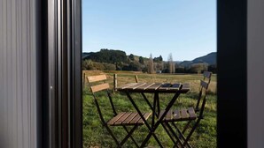 Un área de estar al aire libre con una mesa y sillas, con vista a un campo cubierto de césped y colinas.