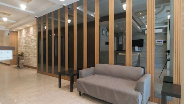 A modern lobby with a sofa, a reception desk, and a wall with vertical wooden panels. - RedDoorz Plus @ Bez Tower and Residences San Juan (San Juan)
