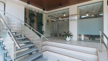 A staircase with metal railings, a potted plant, and a view of a modern interior space with glass walls.