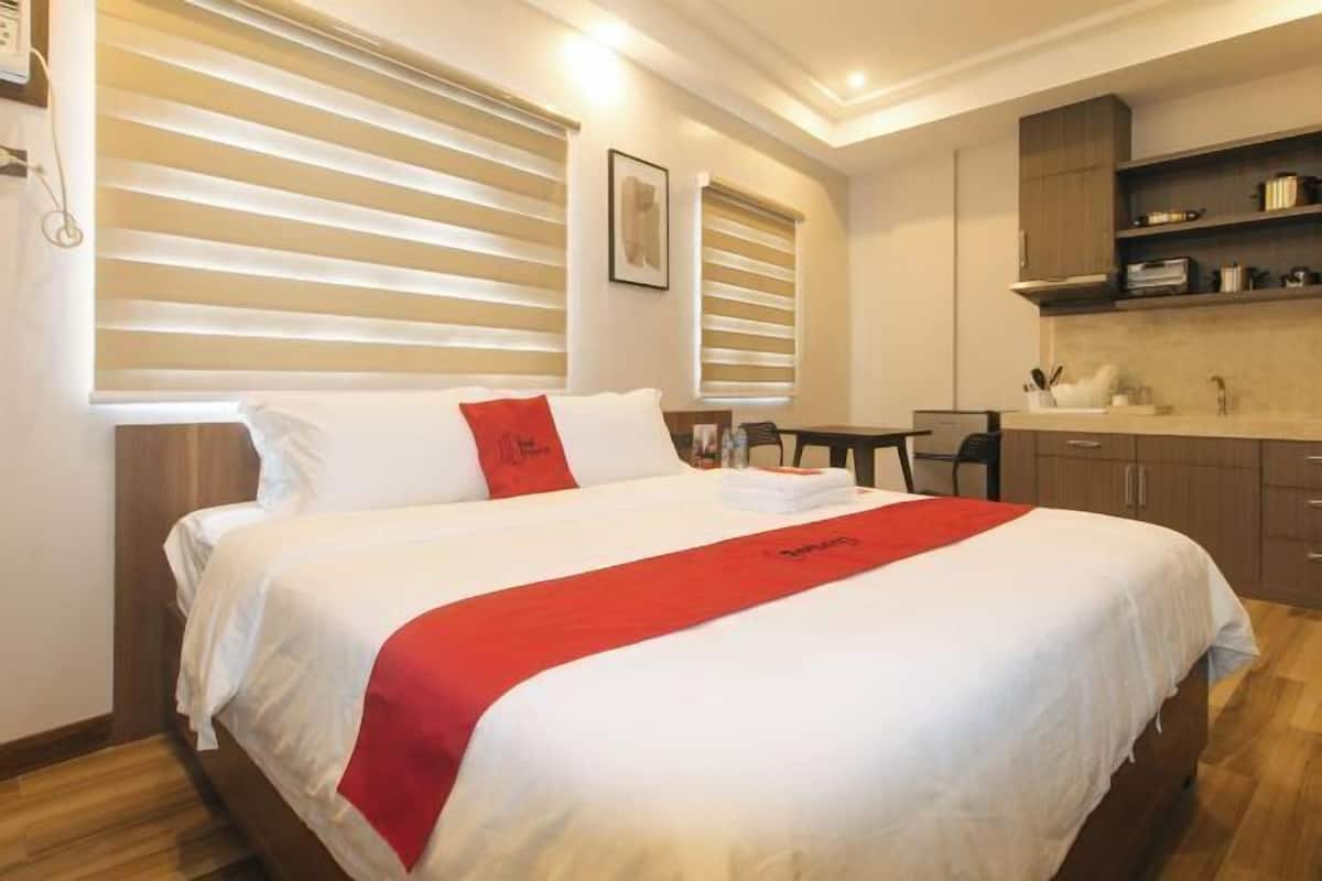 Une chambre d’hôtel avec un lit, un bureau et une kitchenette.
