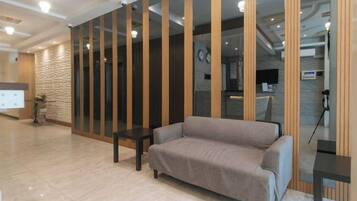 A modern lobby with a sofa, a reception desk, and a glass partition.