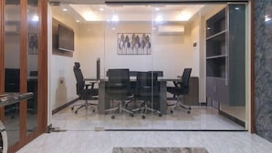 A modern meeting room with glass walls, a conference table, and black office chairs. - RedDoorz Plus @ Bez Tower and Residences San Juan (San Juan)