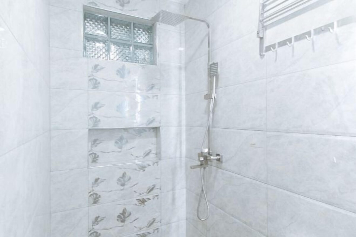 A shower with a handheld showerhead and a wall-mounted towel rack.