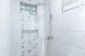 Ducha con cabezal de ducha de mano y toallero adherido a la pared.