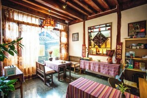 A cozy room with a wooden ceiling, a dining table with chairs, a bench, and a bookshelf. - Songhe Boutique Hostel (Lijiang)