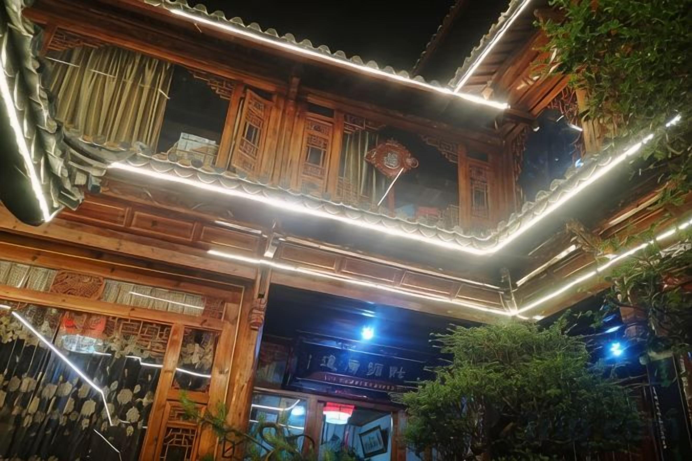 A traditional wooden building with a tiled roof and illuminated by string lights.
