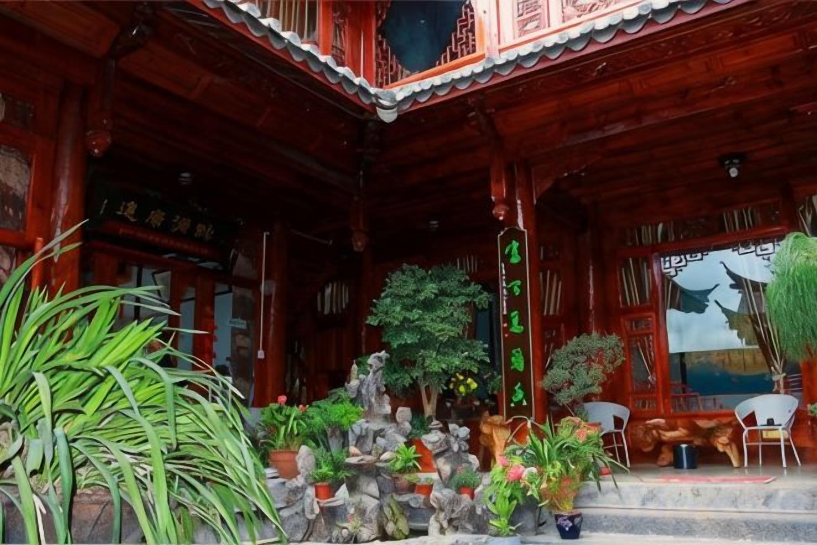 A traditional wooden building with a covered porch, potted plants, and a stone pathway.